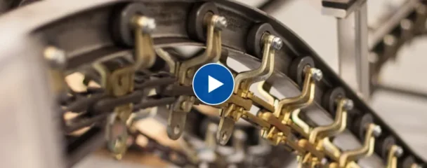 Overhead conveyor chain with brass attachments running around a curved track